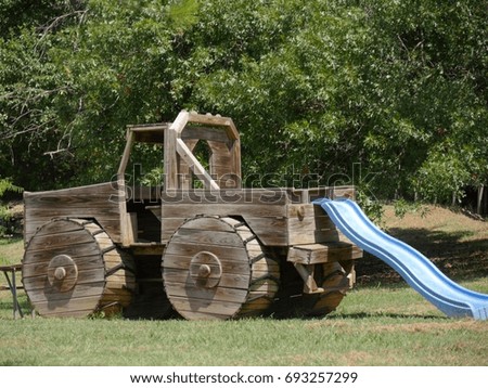 Big wooden toy truck with a plastic slide attached at the rear at a children’s playground