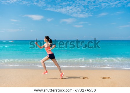 side view photo of professional young female athlete going to workout and running on beach to train endurance.