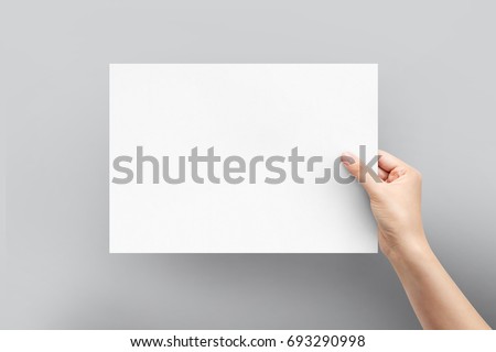 Close up women holding paper blank a4 size for letter paper on a grey background. Royalty-Free Stock Photo #693290998
