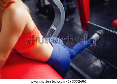 Close-up of the girl's buttocks in the gym is engaged in a simulator for braces, hardened priests. The concept of doing sports, fitness.