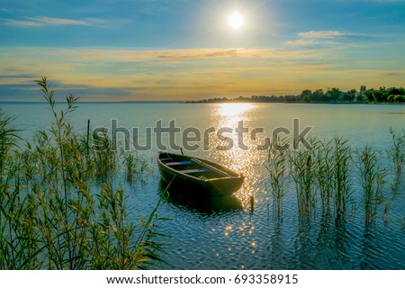Rowing boat on lake at sunset
Small wooden rowing boat on a calm lake at sunset reed
 Royalty-Free Stock Photo #693358915