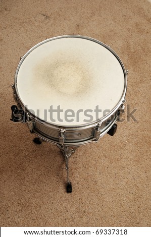 Above view of a snare drum on a stand on a carpet.