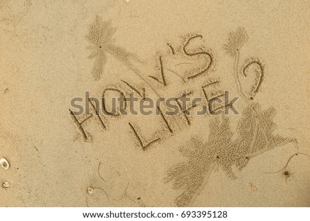 Handwriting  words "HOW'S LIFE?" on sand of beach.
