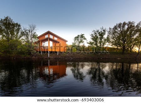 Contemporary wooden single family house. Retreat rental. Perfect getaway. Wooden house on a island with oaks. organic architecture. Wooden minimalistic house with big panoramic windows.  Royalty-Free Stock Photo #693403006