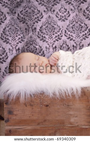 Newborn baby sleeping with damask wallpaper background.
