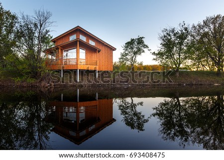 Contemporary wooden single family house. Retreat rental. Perfect getaway. Wooden house on a island with oaks. organic architecture. Wooden minimalistic house with big panoramic windows.  Royalty-Free Stock Photo #693408475