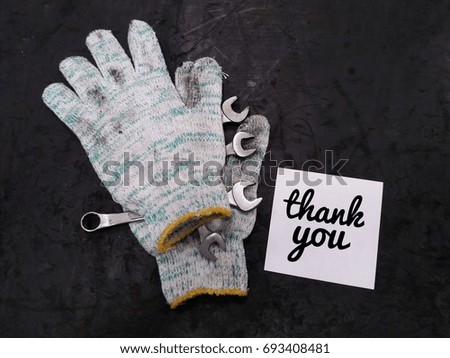 Concept image of dirty hand glove with tools and paper noted word - Thank you on black board/selective focus/vintage