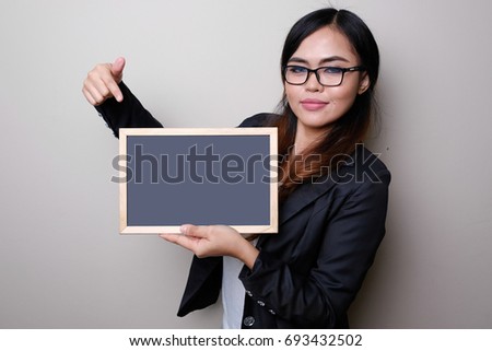 Business woman show something on blank black board