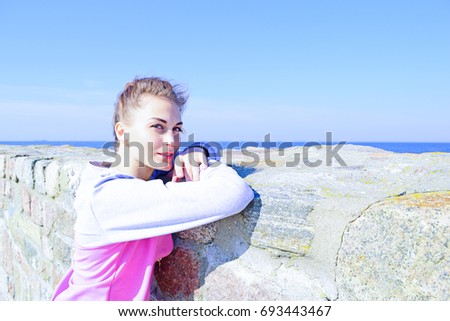 Portrait of a sporty young girl on stone wall background beside nature. cold filter
