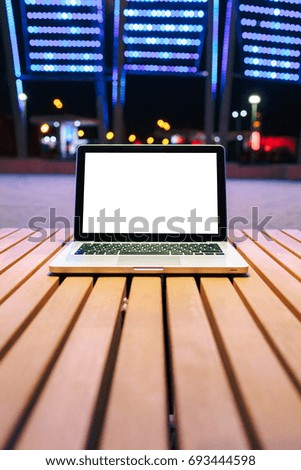 Mockup image of laptop with blank white screen on vintage wooden table in nature outdoor park.
