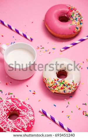 Donuts with icing and milk on pastel pink background. Sweet donuts.
