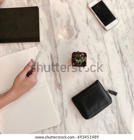 Workplace in modern style with  diary, black wallet, smart phone  and marble desk. Flat lay 