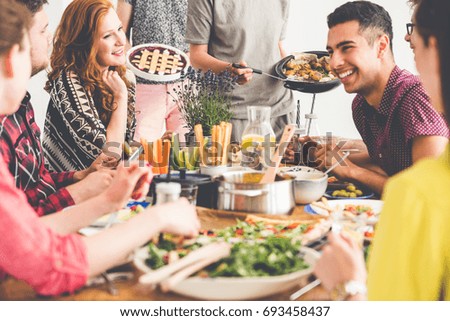 Healthy smiling friends enjoy meeting at communal table with hummus, falafel and vegetables