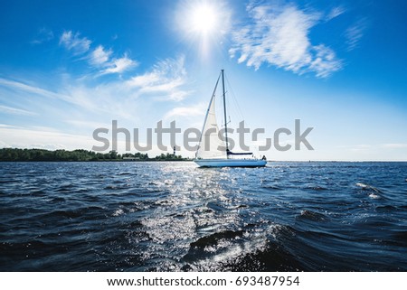 Yacht with white sails in dark blue open space. The good wind fills sails on a sunny summer day.