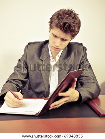Serious rich successful guy signing documents inside his office