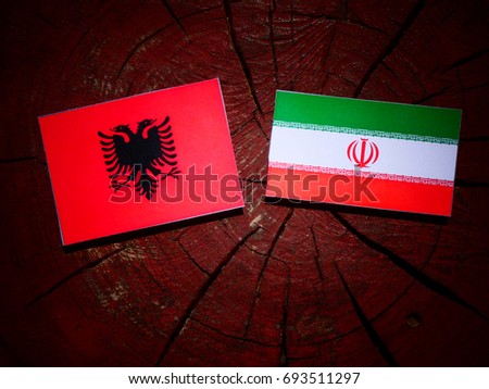 Albanian flag with Iranian flag on a tree stump isolated
