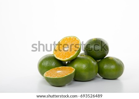 Half sliced, whole green mandarins, tangerine or clementine fruits lying on empty white background, copy space. Side view. Studio shot. Beautiful citrus fiber food for advertisement, poster. Close-up.