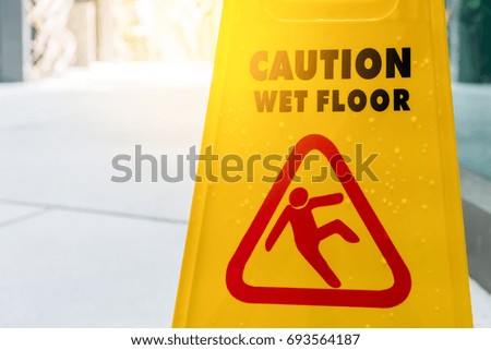 Caution wet floor sign on ground with sun light.