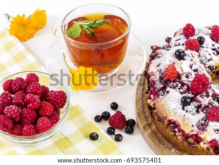 Pie with raspberries and tea with mint on a light background.