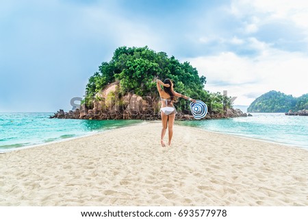 Traveler woman in bikini her hand holding big hat relaxing on destinations beach and small island, Koh Pak Bia island, Separated sea, Andaman sea, Krabi, Travel in Thailand