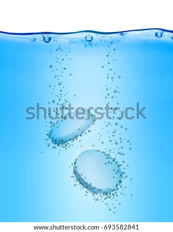 Two medical pills dissolves in blue water 