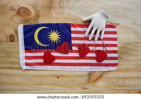 A Malaysian a red love shapes and a hand : symbol of unity on a wooden background.  Concept for 60th year of Malaysian Independence Day.