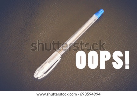 Oops! with pen on wooden table