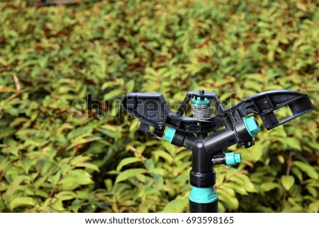 A Plastic Springer Water And A Green Plant Field Garden Royalty-Free Stock Photo #693598165