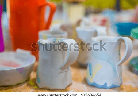 Colored unfinished ceramic cups on the wooden surface