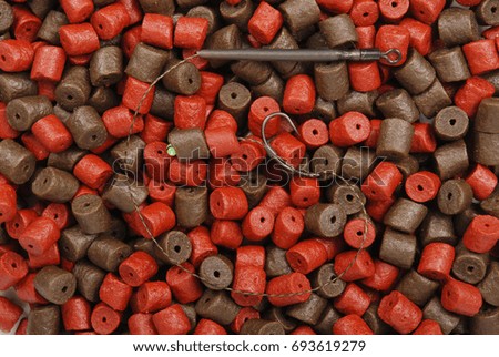 Fishing bait with hook and brown with red pre-drilled halibut pellets for carp fishing  background