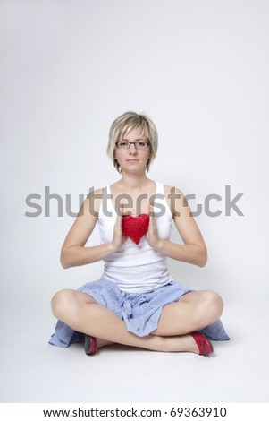 Portrait of beautiful young woman holding red heart on white background