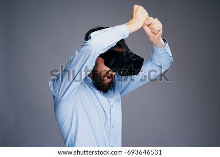A man with a beard screams holds a visually knife playing in a 3d game of virtual reality on a gray background                               
