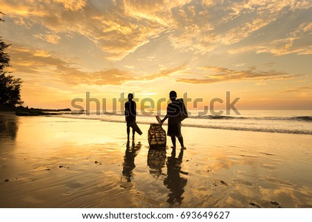 Beautiful sunset with reflection. Two unknown kids silhoeutte with their fishing tools appear on image. 