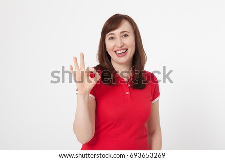 Smiling attractive middle aged woman showing thumbs up, okay. Isolated. Copy space. Mock up. Menopause. Summer holidays