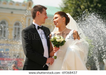 Enamoured groom and the bride against a fountain. Royalty-Free Stock Photo #69368437