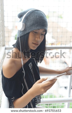 Asian girls listen to music from the headphone and Her smartphone.(outdoor)