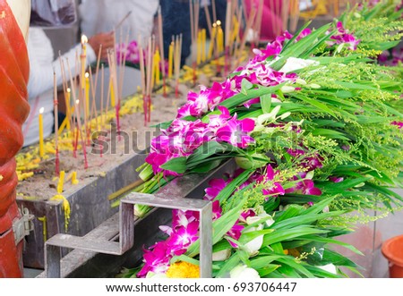 Close up view. People bring Dendrobium spp. flowers candles and incense for worship Buddha.