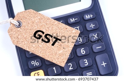 Business Concept. Closeup of calculator, wooden tag with word GST on white background. Selective focus and crop segment.