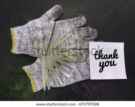 Concept image of dirty hand glove with level gauge and paper noted word - Thank you on the black board/selective focus/vintage