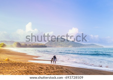 Asian family, dad, and son, enjoying their time at a beach in Phuket, Thailand, with view of beautiful sea and sky in background, good for positive feeling theme