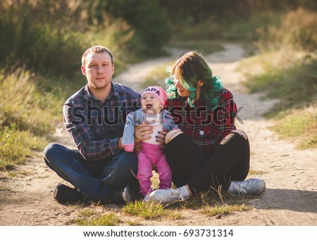 Family photo session in a park with a small daughter in the summer in the fresh air