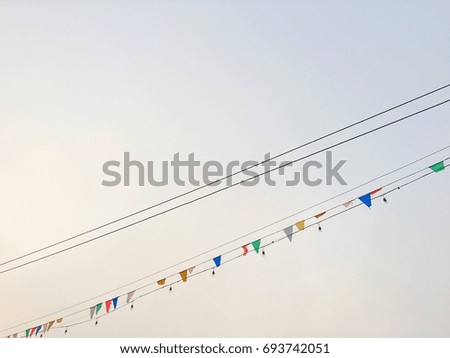 The black wires and colourful flags hang on black string with clear sky background