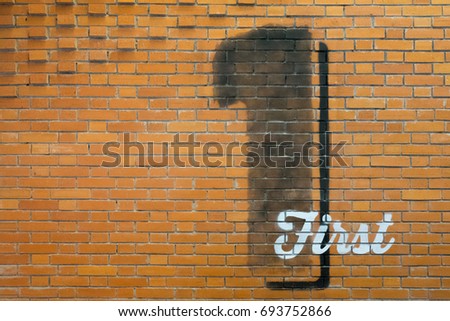 Black number one and white letter 'first' on warm brown brick wall - background