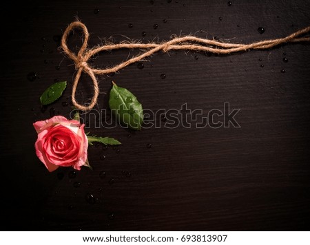 Rose and rope on black wood floor.