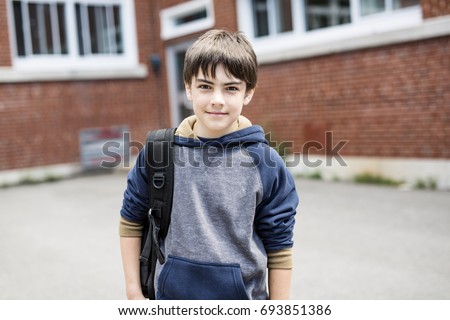 A Nice Pre-teen boy outside at school having good time Royalty-Free Stock Photo #693851386