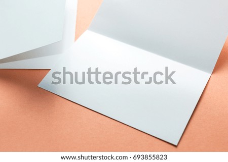 Blank square two-leaf brochures isolated on orange background. Space for text.