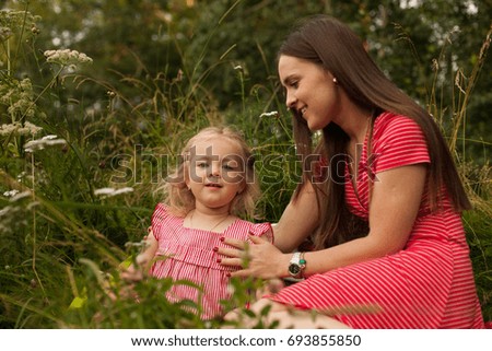 A young mother and her little daughter, happy family outdoors