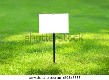 A signboard in the picturesque green grass for your signature. Green lawn background.