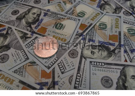 Silver bitcoin on hundred-dollar bills