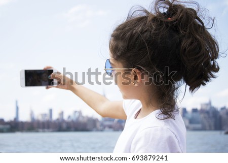 Cute Girl taking a self with New York skyline on the background.